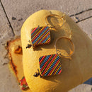 Σκουλαρίκια κρίκοι με κρεμαστούς ρόμβους με πολύχρωμες ρίγες.